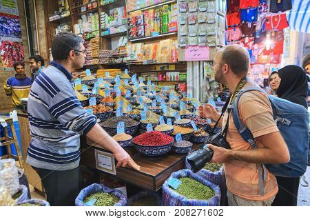 Fars Province Shiraz Iran - 19 april 2017: Iranian seller of spices and dried fruit helps travelers are choosing to buy goods.