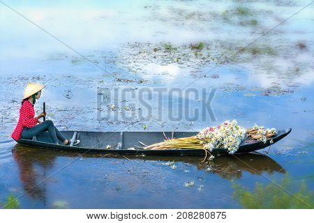 Long An, Vietnam - September 24th, 2017: Farmers carrying lilies boating through rural marshland in early morning brought agricultural trade market in the Mekong Delta, Long An, Vietnam