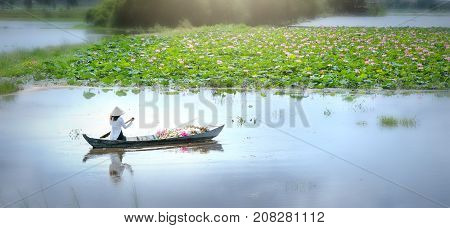 Long An, Vietnam - September 24th, 2017: Farmers carrying lilies boating through rural marshland in early morning brought agricultural trade market in the Mekong Delta, Long An, Vietnam