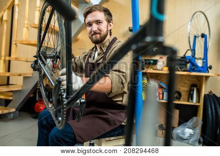 Successful repair master with bicycle looking at camera during work