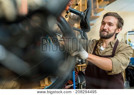 Professional repairman with spanner fixing detail of bicycle wheel
