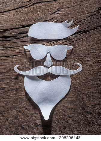 Hipster's definicial facial look cut from paper on the wooden background.