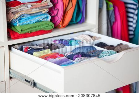 Neatly Folded Clothes With Accessories In Chest Of Drawers
