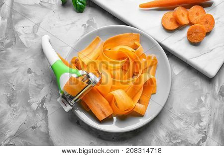 Plate with triple slicer and raw carrot on grunge background
