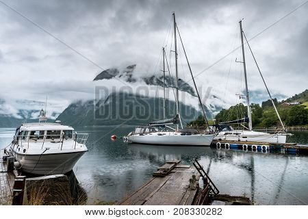 Amazing nature landscape view of Hardangerfjord fjord surrounded by foggy mountains. Sailing vessels or ships. Nature lake. Forest natural. Location: Scandinavian Mountains, Norway. Beauty world.