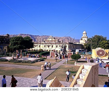 JAIPUR, INDIA - NOVEMBER 24, 1993 - Elevated view of people looking at the giant sundial known as the Samrat Yantra at Jantar Mantar Jai Singhs Observatory with the City Palace also known as the Chandra Mahal to the rear Jaipur Rajasthan India, November 2