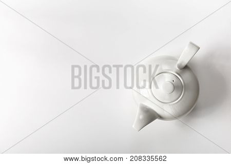 From above view of minimalist composition with white porcelain teapot on white surface.