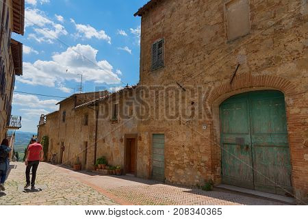 Pienza, Italy - May 27, 2017: Beautiful narrow street with sunlight and flowers in the small magical and old village of Pienza, Val D'Orcia Tuscany.