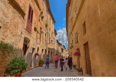Pienza, Italy - May 27, 2017: Beautiful narrow street with sunlight and flowers in the small magical and old village of Pienza, Val D'Orcia Tuscany.