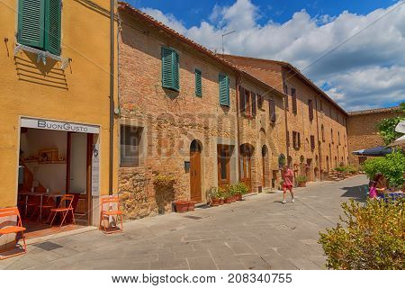 Pienza, Italy - May 27, 2017: Beautiful narrow street with sunlight and flowers in the small magical and old village of Pienza, Val D'Orcia Tuscany.