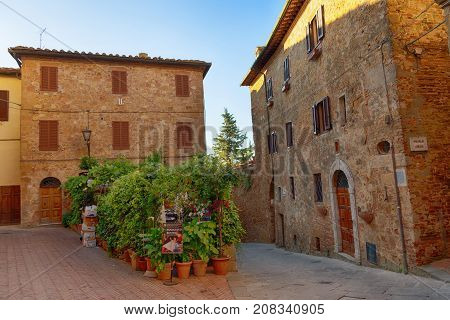 Pienza, Italy - May 27, 2017: Beautiful narrow street with sunlight and flowers in the small magical and old village of Pienza, Val D'Orcia Tuscany.