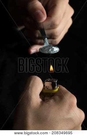 The man prepares drugs with spoon and lighter drug addiction