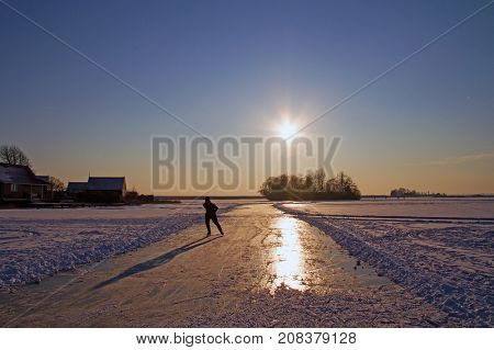 Lonely isce skating in the countryside from the Netherlands in winter at sunset