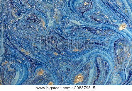 Marbled blue abstract background with golden sequins. Liquid marble ink pattern