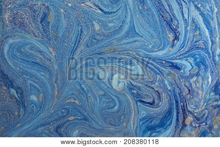 Marbled blue abstract background with golden sequins. Liquid marble ink pattern