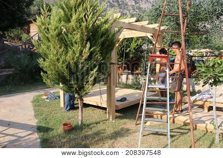 20TH JULY 2017, KABAK,TURKEY: Turkish workmen building a swing seat pergola in an olive garden at kabak, turkey, 20th july 2017