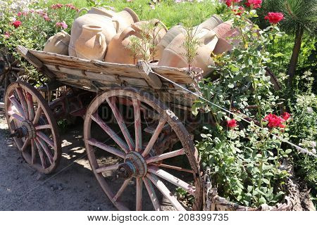 An old wooden wagon loaded with old ceramic clay pots .