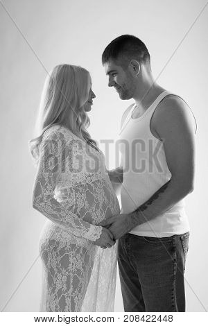 Beautiful pregnant couple in love on the background. Hands of husband on the tummy of his pregnant wife. Young man tenderly stroked pregnant belly of his wife. Husband kissing pregnant belly.