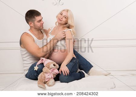 Beautiful pregnant couple in love on the background. Hands of husband on the tummy of his pregnant wife. Young man tenderly stroked pregnant belly of his wife. Husband kissing pregnant belly.