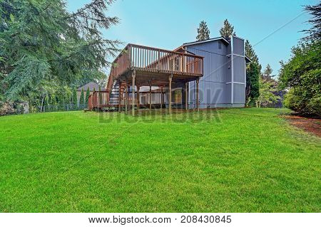 Backyard View Of Grey Rambler House With Upper And Lower Decks