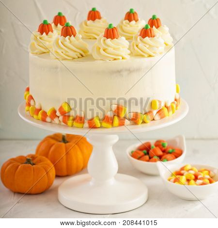 Pumpkin spice layered cake with cream cheese frosting decorated with candy, dessert for Halloween and Thanksgiving