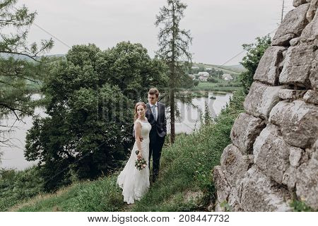 Beautiful Gorgeous Bride And Groom Posing. Happy Wedding Couple Hugging And Embracing At Old Castle.