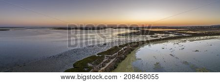 Sunset aerial panoramic seascape view of Olhao salt marsh Inlet waterfront to Ria Formosa natural park. Algarve. Portugal.