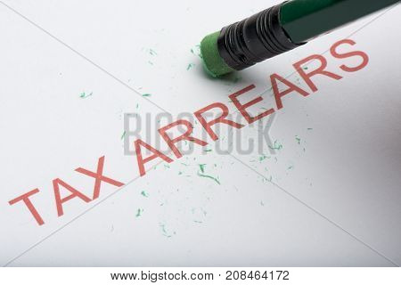Pencil Erasing The Word 'tax Arrears' On Paper