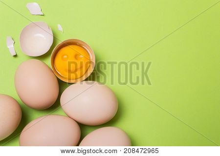 One chicken egg is broken and the yolk smiles. Cheerful breakfast. Copy space for text