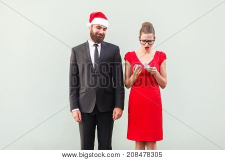 Proud Man In Christmas Cap Looking A Gift. Frustrated Woman Holding Gifts.