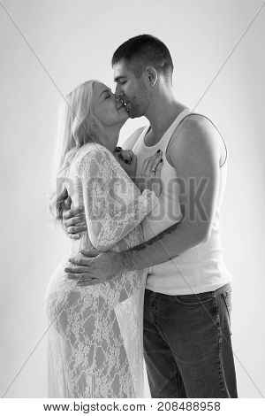 Beautiful pregnant couple in love on the background. Hands of husband on the tummy of his pregnant wife. Young man tenderly stroked pregnant belly of his wife. Husband kissing pregnant belly.