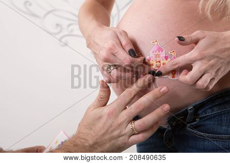Beautiful pregnant couple in love on the background. Hands of husband on the tummy of his pregnant wife. Young man tenderly stroked pregnant belly of his wife. Husband kissing pregnant belly.