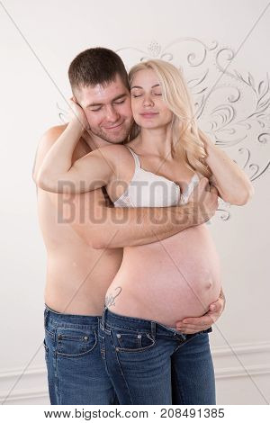 Beautiful pregnant couple in love on the background. Hands of husband on the tummy of his pregnant wife. Young man tenderly stroked pregnant belly of his wife. Husband kissing pregnant belly.