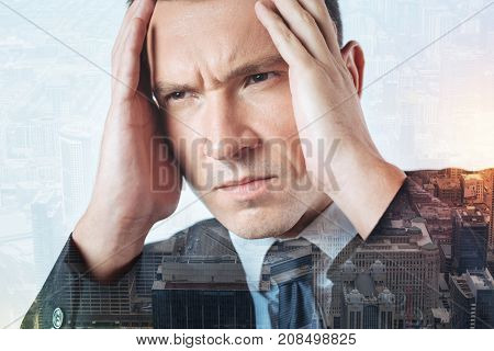 Deep thinking. Gloomy serious strict man putting his hands on a head while thinking about an urgent problem