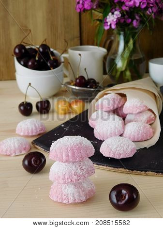 Pink berry marshmallows (zephyr) is scattered out of a paper bag surrounded by cherries