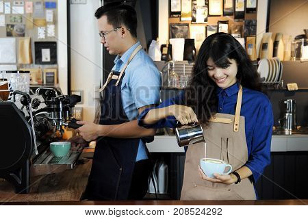 Two of asian barista making latte or cappucino coffee in coffee shop. Cafe restaurant service Small business owner food and drink industry concept.