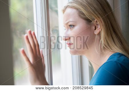 Sad Young Woman Suffering From Depression Looking Out Of Window