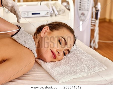Body massage of silver threaded gloves at beauty salon. Electric stimulation skin care of woman. The best spa salon. Beautician wearing electricity glove. Hardware cosmetology.