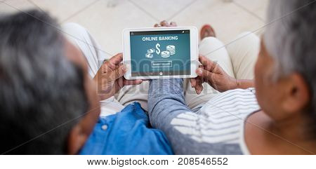 Online banking with dollar symbol on phone screen against senior couple using digital tablet at home