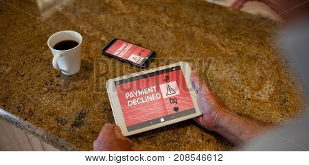 Payment declined text on phone screen against senior man holding digital tablet in the kitchen