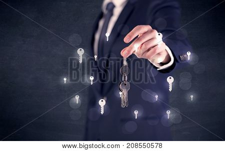 Businessman in suit holding keys with keys graphics around and dark background