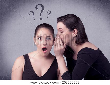 A teenager girl looking confused with drawn question marks above the head, while a girlfriend whispers something in her ear concept.