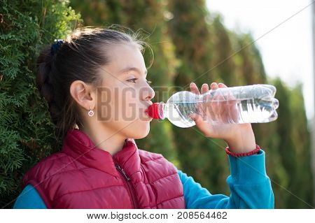 Beautiful girl is drinking water the hot sun in the park. Healthily concept. Healthy lifestyle concept. copy space. Portrait happy smiles beautiful girl . Portrait smiles girl. girl drinking water