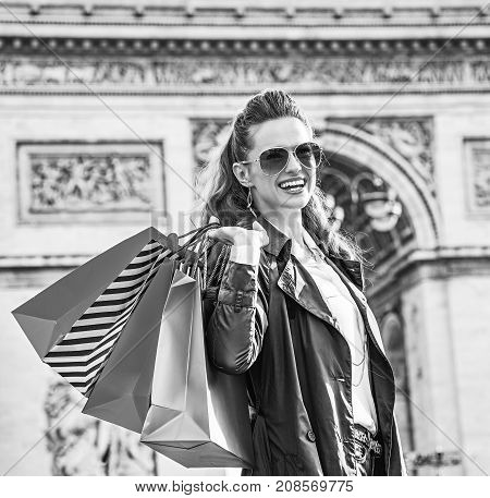 Stylish autumn in Paris. smiling elegant woman with shopping bags near Arc de Triomphe in Paris France looking into the distance