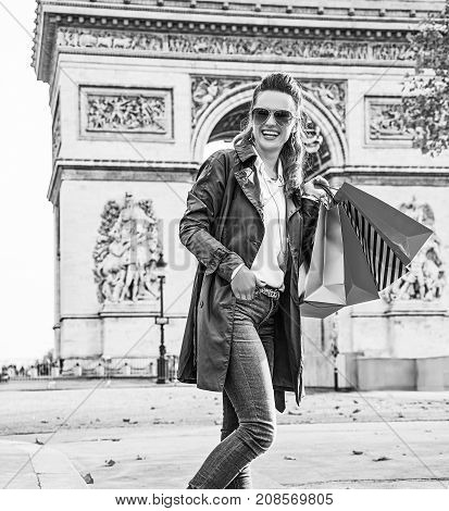 Stylish autumn in Paris. Full length portrait of happy trendy fashion-monger in sunglasses with shopping bags in Paris France