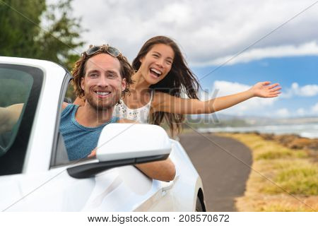 Car road trip couple summer fun on travel vacation freedom. Happy free people in convertible cabriolet driving. Asian woman carefree with open arms cheering joyful. Friends going on holidays.