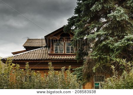Old Russian wooden house among trees. The atmosphere of old Russian village. Ancient Russian wooden house from logs among old trees.