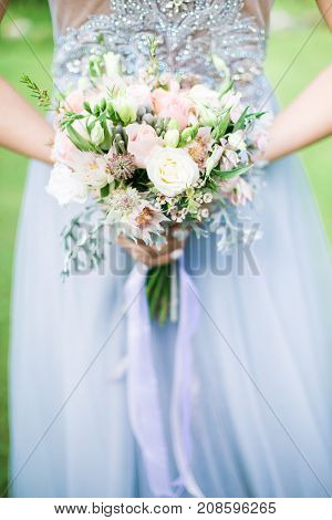Bride holding wedding bouquet outdoors, daylight rustic style