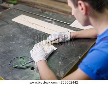 A carved plate on which the patterns and inscriptions are burned out that the master in blue overalls handle with a special tool