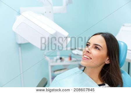 Happy long-haired girl in stomatology policlinic. A girl sits in the dentist's room and pleased with the service. Close-up of girl. Medical concept.